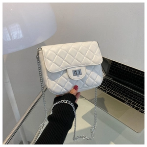 First-person view of white quilted crossbody bag with silver chain on a modern desk