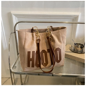 Detail of beige tote bag with HOOJO lettering and gold chain leather shoulder straps