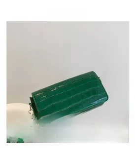 Detail shot of dark green crocodile texture baguette bag with polished gold hardware buckle
