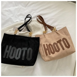 Detail view of khaki suede tote bag featuring HOOTO lettering and gold chain strap