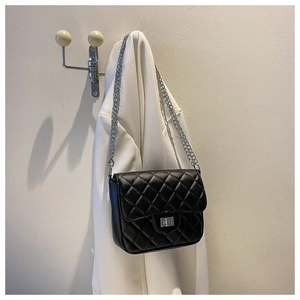 Detail of black quilted leather crossbody bag with silver chain strap and metal lock