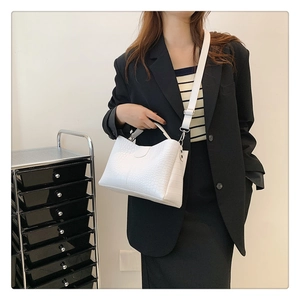 Sac à main blanc à motif crocodile avec bandoulière porté par un mannequin en blazer