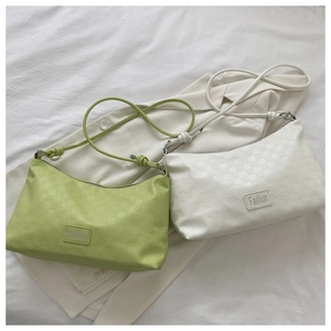 Detail of light green and beige underarm bags with checkered texture and knotted straps