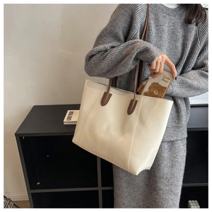 Close-up of cream large tote bag with brown straps and vertical stitching detail