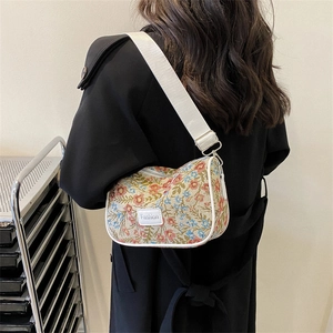 Floral embroidery underarm bag with white leather trim and fashion strap shown on model