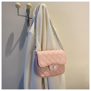 Detail view of pink quilted handbag with silver clasp and chain strap on coat