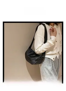 Detail of a black nylon crescent shoulder bag with pleated texture and adjustable strap