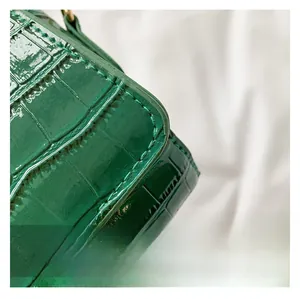 Detail of dark green crocodile embossed baguette bag showing patent leather texture