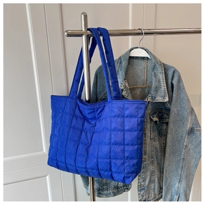 Detail of royal blue quilted puffer tote bag with wide shoulder strap and waterproof nylon