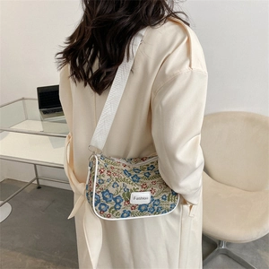 Floral print crossbody bag with fashion tag and white strap shown in minimalist interior