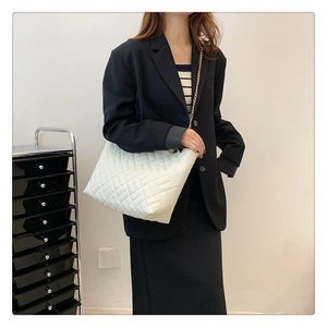Borsa a tracolla trapuntata bianca con catena dorata indossata su un blazer nero