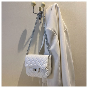 Detailed view of white quilted faux leather bag with silver chain strap and twist lock