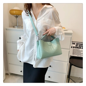 Sac fourre-tout vert clair à motif crocodile porté dans une scène de vie moderne