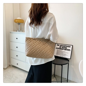 Borsa tote trapuntata con catena dorata indossata da una modella in un ambiente moderno