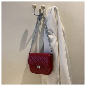 Detail of red quilted faux leather handbag featuring silver twist lock and chain strap