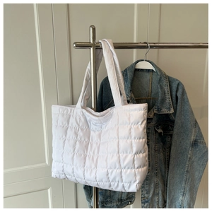 Close-up of white quilted tote bag featuring padded handles and soft nylon texture