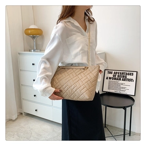 Dettaglio della borsa shopping trapuntata beige con catena dorata indossata da modella