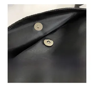 Detail of the high-quality magnetic snap closure on a black nylon tote bag
