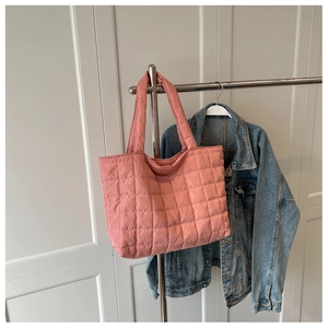 Detailed shot of pink quilted tote bag with square texture hanging on metal stand