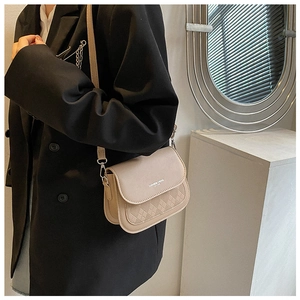 Detail of beige saddle bag with diamond embossed texture worn with a black blazer