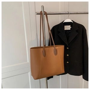 Detail of minimalist caramel leather tote bag with slim handles for business commute