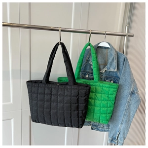 Detailed view of quilted puffer tote bags in black and green with light padding
