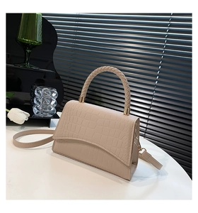 Detail of woven handle and crocodile pattern on chic beige crossbody handbag
