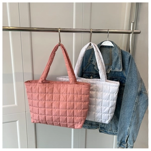 Macro view of pink and white quilted puffer tote bags in glossy nylon fabric