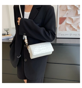 Detail of white crocodile-effect baguette bag with gold hardware and adjustable strap