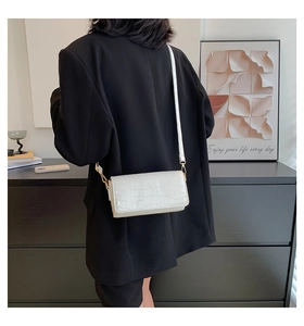 Close-up of white crocodile pattern baguette bag with glossy texture and metal buckle