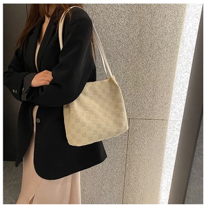 Détail d'un sac cabas tissé crème avec un motif en damier texturé et élégant