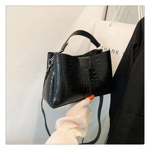 Détail du sac seau noir à motif crocodile avec poignée et bandoulière réglable