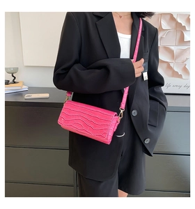 Hot pink crocodile embossed baguette bag worn over the shoulder with black blazer outfit