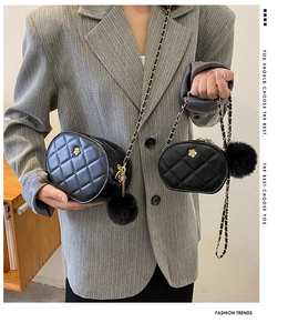Detail of two black quilted chain bags with gold flower logos and plush pompom charms