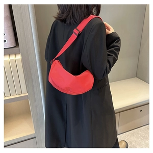 Chic red crescent-shaped nylon crossbody bag worn over a sleek black blazer
