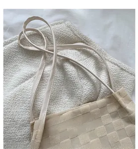 Détail du sac à bandoulière beige montrant la texture gaufrée unique du tissu chic