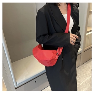 Chic red nylon crescent bag worn over a black blazer for a stylish contrast look