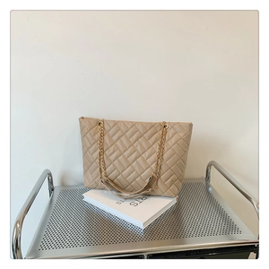 Dettaglio della borsa tote trapuntata beige con spalline a catena dorata su carrello