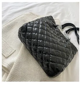 Detailaufnahme der schwarzen glänzenden Stepptasche mit silberner Kette und Lederriemen