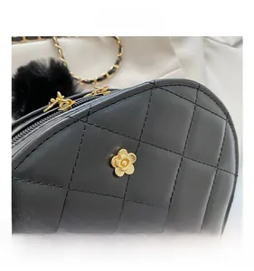 Detail of quilted leather bag with gold camellia clasp and fuzzy pompom charm