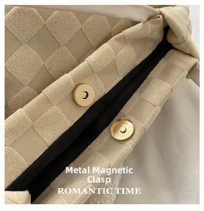 Détail du fermoir magnétique en métal sur un sac cabas en tissu à carreaux beige