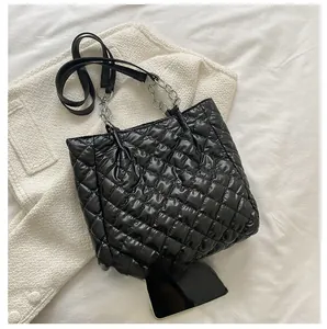 Detail der schwarzen Stepptasche mit silberner Kette und glänzender Nylonstruktur