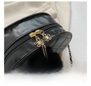 Close-up of golden petal zipper head and black plush ball on quilted chain bag