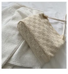 Détail de la texture d'un sac cabas beige à carreaux et d'une jupe en tweed blanc