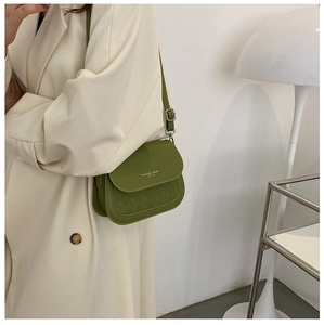 Close-up of green crossbody saddle bag featuring quilted texture and adjustable leather strap