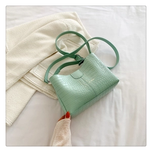Détail du sac bandoulière vert menthe avec motif crocodile et bandoulière assortie
