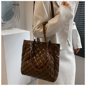 Braune gesteppte Puffer-Tasche mit Kettenriemen am Modell in minimalistischer Umgebung