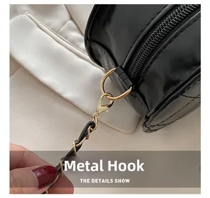 Detail of gold hardware hooks and chain strap on black quilted oval shoulder bag