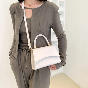 Elegant ivory crossbody bag with crocodile texture and woven handle on a fashion model