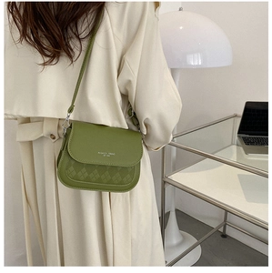Detail of green retro crossbody saddle bag with quilted pattern and fashion text